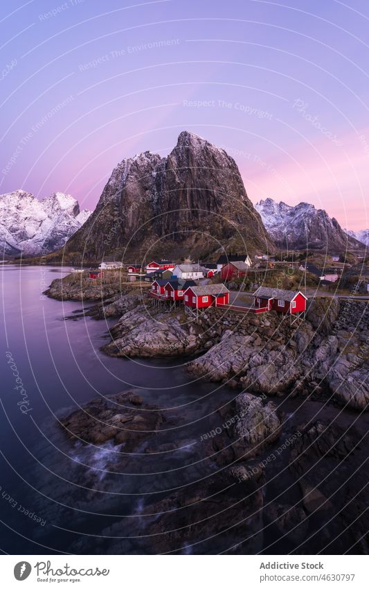 Fishing village near snowy mountains at sundown sea shore sunset house ridge cloudless sky winter lofoten Hamnoy norway pink sky coast cottage landscape scenic