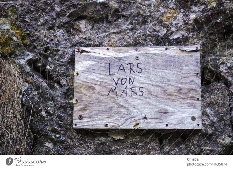 Wooden sign by the roadside with style flower; Lars from or from Mars doesn't matter ;-) in children's writing Felt-tipped pen Characters children's handwriting