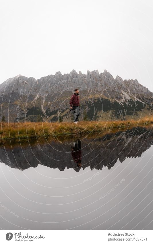 Man admiring mountains near lake man nature traveler shore landscape admire trip male walk fog scenic reflection tourism grass coast hill highland mist guy