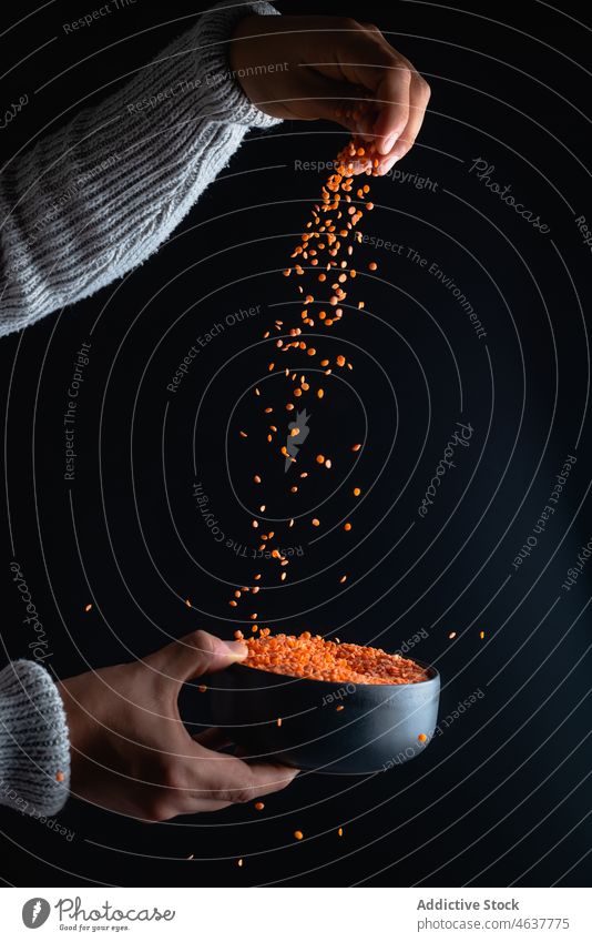 Anonymous person pouring red lentils legume culinary organic food raw uncooked bowl hand fresh natural prepare ingredient cuisine add product many light fill