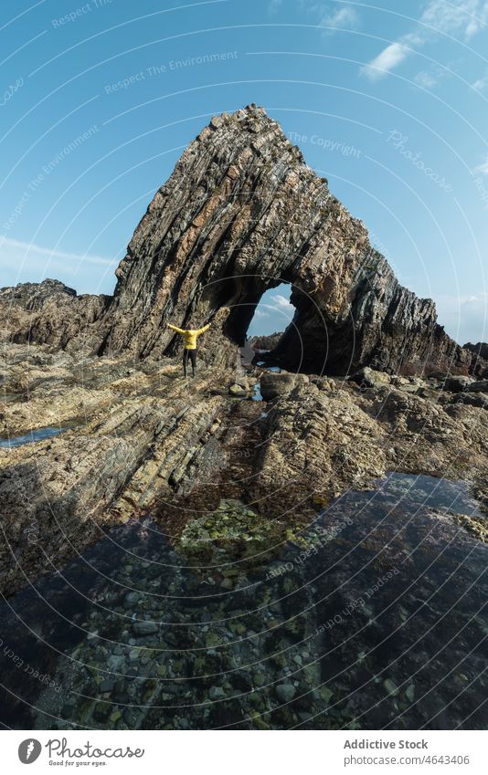 Anonymous traveler near rock on shore trip adventure beach cliff sea water coast nature stone asturias spain formation rough cloudy cudillero rocky environment