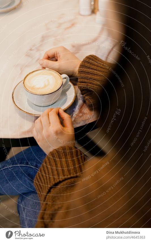 Woman drinking coffee - hands holding a cup of cappuccino coffee at cafe on marble table caffeine desk liquid copy space coffee cup break relaxation no people