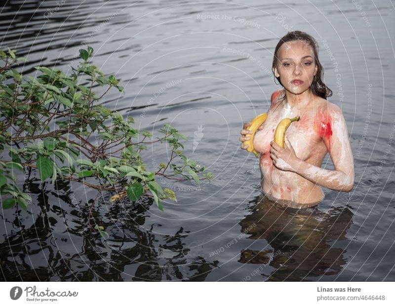 With her sexy curves in body paint this girl is enjoying the water. Naked  brunette model is holding bananas in her hands for censored purposes in  this case. Gorgeous woman is all