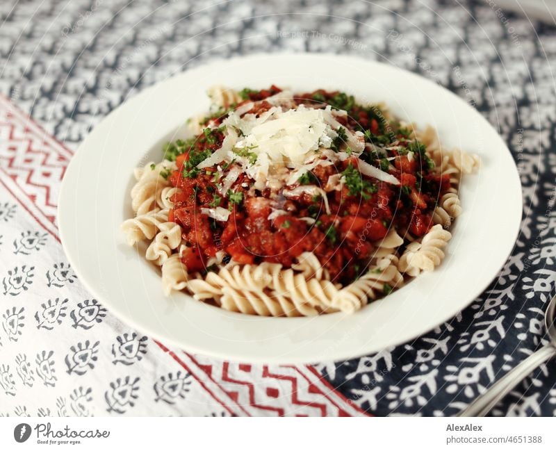 Soup plate with spirelli/fusilli and sauce Bolognese with parmesan cheese and fresh basil tablecloth Pattern Plate Cutlery Spoon Porcelain pasta Tomato sauce