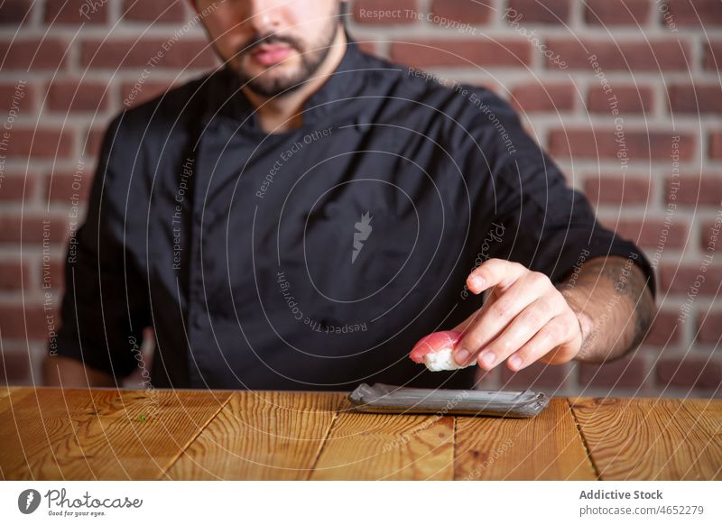 Unrecognizable chef serving sushi on plate tuna fish serve japanese asian food seafood culinary cuisine tasty fresh meal restaurant oriental delicious rice