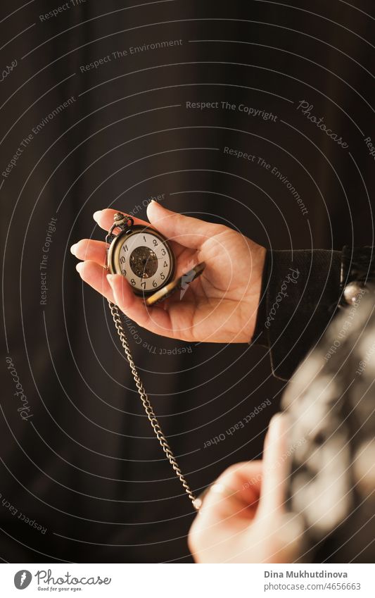 Person holding vintage old chain watch in her hands as a fashion accessory for steampunk style outfit. jewelry design clock aged time blank object abstract