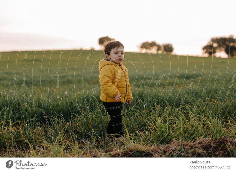 Child with Yellow jacket against grass field childhood Caucasian Infancy Lifestyle Authentic Joy Childhood memory Colour photo Multicoloured Emotions