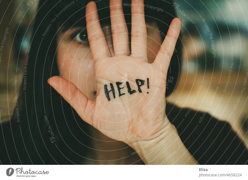 Young woman defensively holds a hand in front of her face on which the word Help is written Woman Protective ask for help Helpless Seeking help