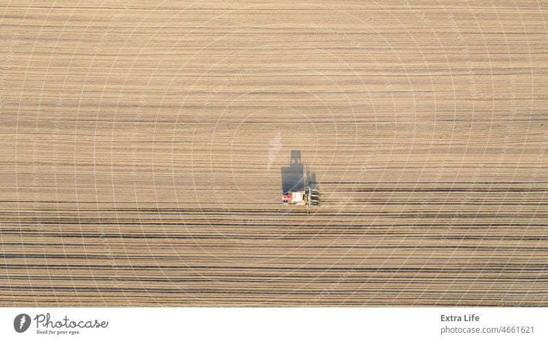 Aerial top view of tractor as dragging a sowing machine over agricultural field, farmland Above Agricultural Agriculture Arable Cereal Corn Cornfield Country