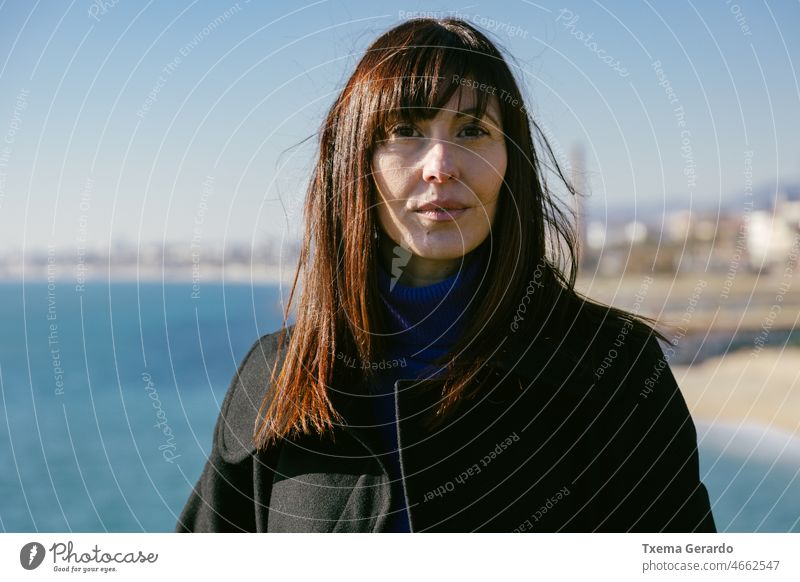 Portrait of woman on the beach on a sunny winter day 45-50 years woman. mature warm femininity headshot outside seasonal serious solitude affection brunette