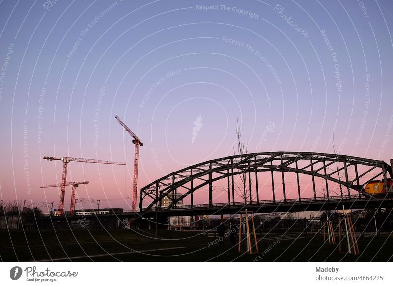 Evening glow and construction cranes behind Deutschherrnbrücke bridge in the evening in the Ostend of Frankfurt am Main in Hesse, Germany urbanity