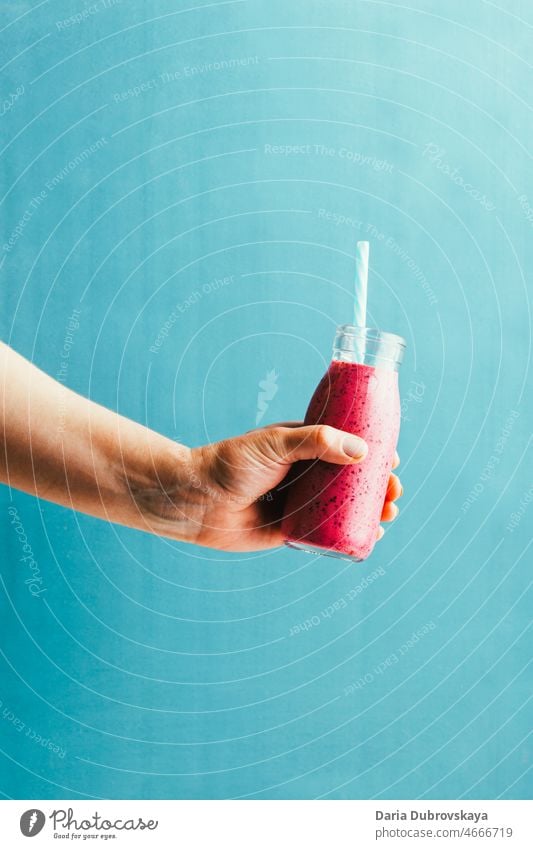 berry smoothie in hand on blue background cooking product ingredient homemade purple yogurt shake recipe detox protein organic glass milk delicious food dessert