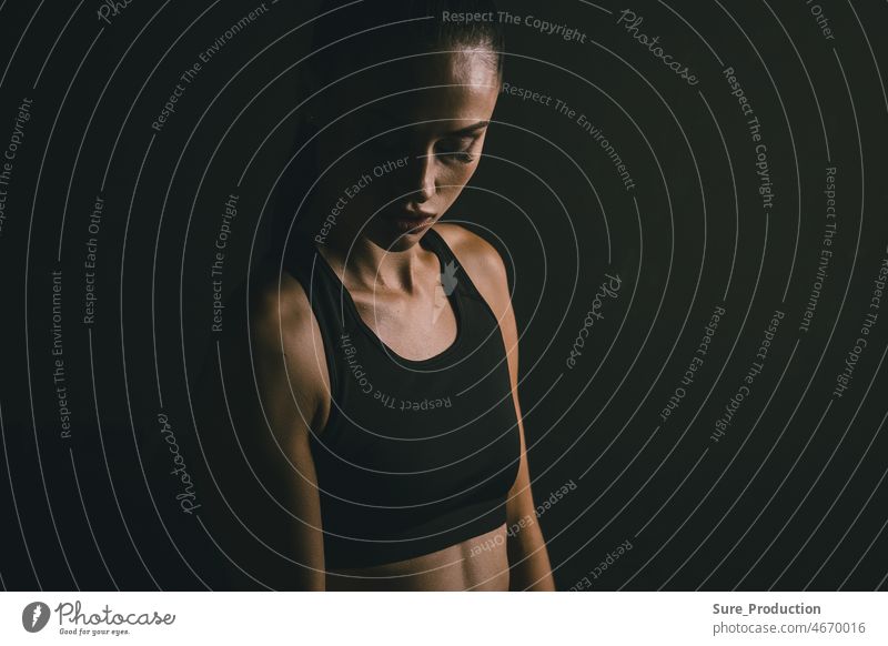Portrait of a young attractive woman sportswoman on a black background during exercise. Concept for sports motivation anger athlete beautiful body confident