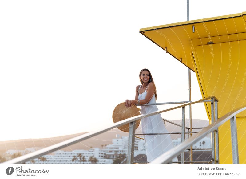 Happy woman resting near lifeguard tower summer happy seaside traveler beach holiday enjoy female young vacation cheerful relax smile carefree station cabin