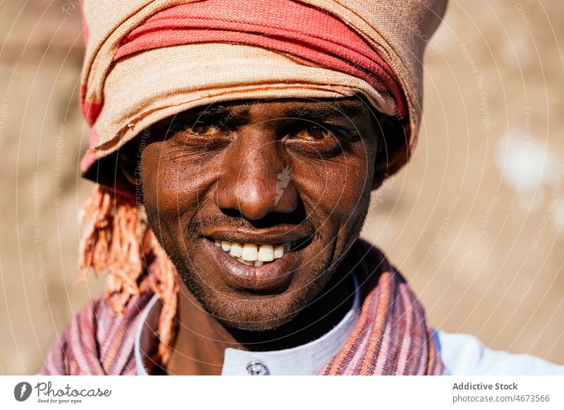 Optimistic Arab man in turban on sunny day in city smile portrait tradition headwear local authentic glad toothy smile male black ethnic arab egyptian optimist
