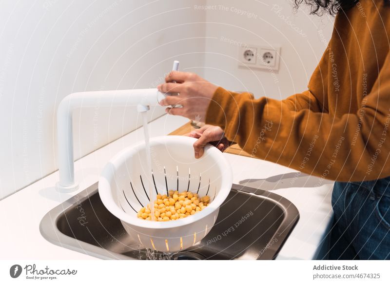 Crop woman washing chickpeas in sink kitchen cook healthy food vegetable culinary cuisine female prepare strainer colander water clean vitamin recipe home lady