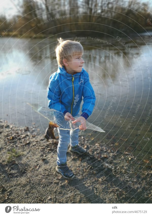 Childhood | nature experience | ice-cold affair. Boy (child) Blonde Blue blue anorak blue jeans Lake pond Ice floe ice plate Water Sand Throw stop Nature out