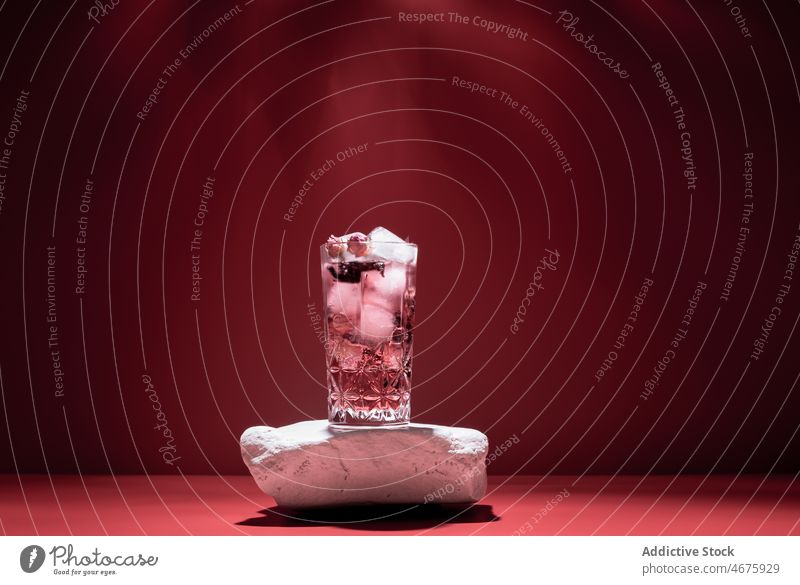 Gin tonic with ice on red background cocktail pink gin alcohol beverage booze glass aperitif studio cold cube drink refreshment frozen liquid ingredient serve