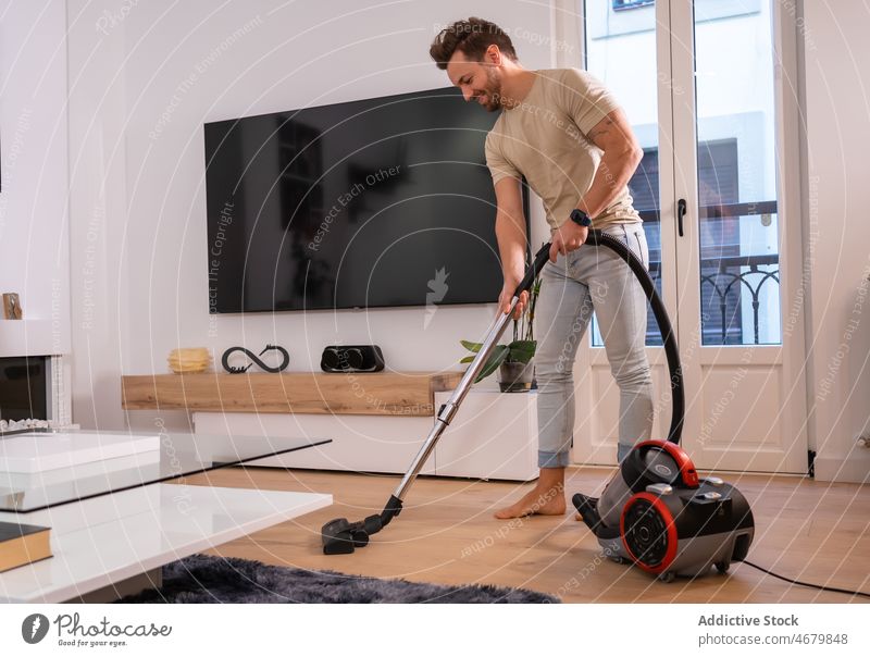 Man vacuuming floor in living room man cleaner household housework routine appliance tidy chore home domestic modern tv male residential process machine