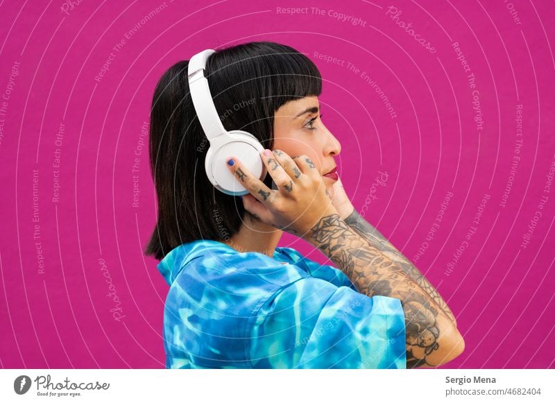 Attractive woman with headphones showing the tattoos on her hands on a pink background Fashion Model Clothing inked girl Headphones Pink Color tattooing Tattoo