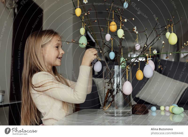 happy caucasian toddler girl eight years old at home in living room with colored easter eggs. Stay home during Coronavirus covid-19 pandemic holiday child kid