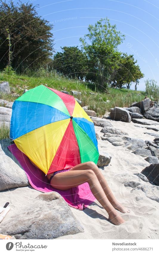 Teenage girl on the beach covered by a sun umbrella, only legs are seen Girl Beach Umbrella Portrait photograph Legs sunny outside Summer Sun Vacation & Travel