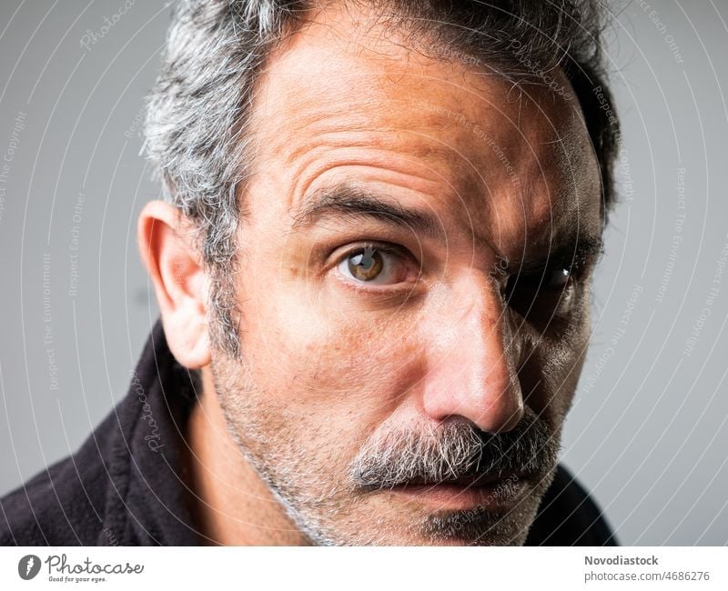 Portrait of a 45 year old caucasian man looking to the camera, with a funny gesture, with a moustache, isolated on grey background portrait alone