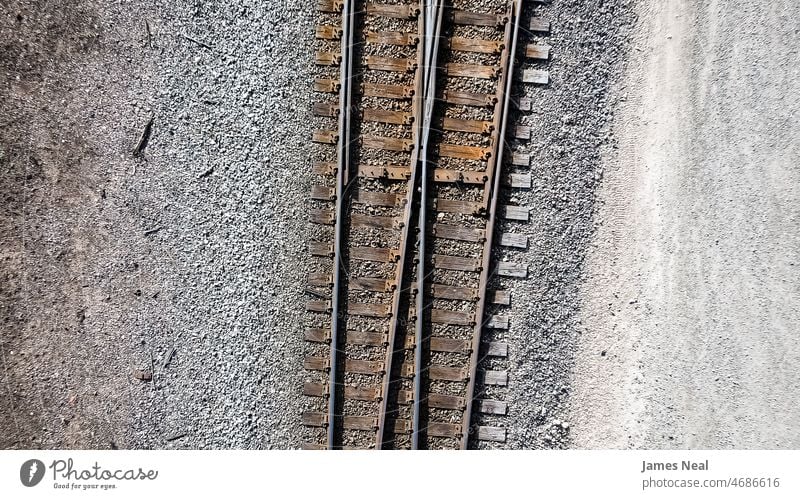 Aerial of pair of old rusty railroad tracks. surface gravel industrial industry transport ground flat view above grunge outside railyard dirty train outdoors