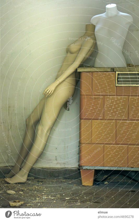 naked, slim, headless, feminine Schaufester doll leans against an old convection oven, on which there is also a torso / giving support Mannequin Naked