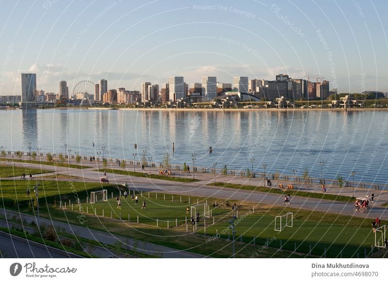 City skyline at sunset at blue hour. City view reflected in river water and football fields. Urban cityscape reflection in water and modern architecture. Vertical urban summer background.