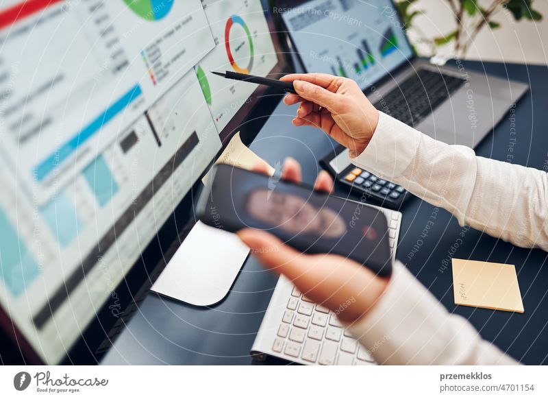 Businesswoman having video chat on mobile phone with her co-worker. Businesswoman working with data on charts, graphs and diagrams on computer screen business