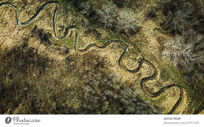 A spiraling stream through autumn landscape nature river creek water grass green bare tree trees natural landscapes background grassy fall season seasons cold