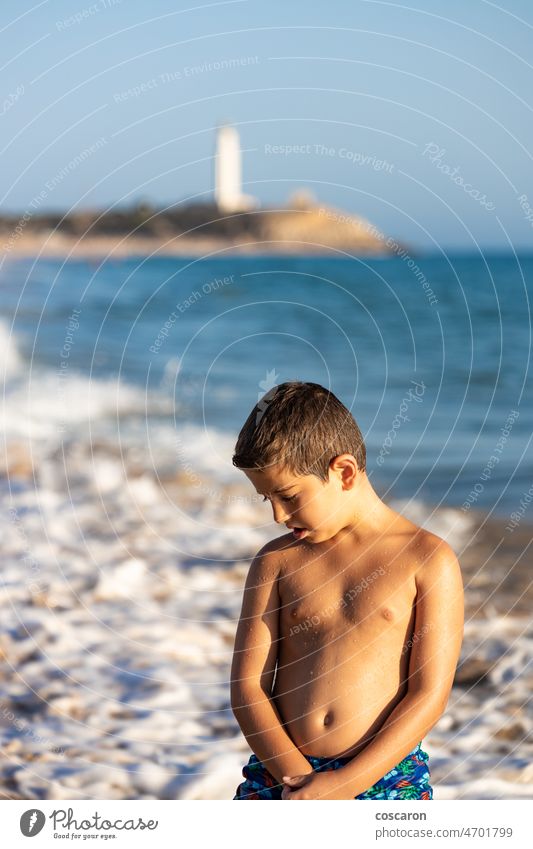 Portrait of a little kid on the ocean with a lighthouse background barbate beach boy cadiz child coast coastline el matador state beach enjoy evening fun golden