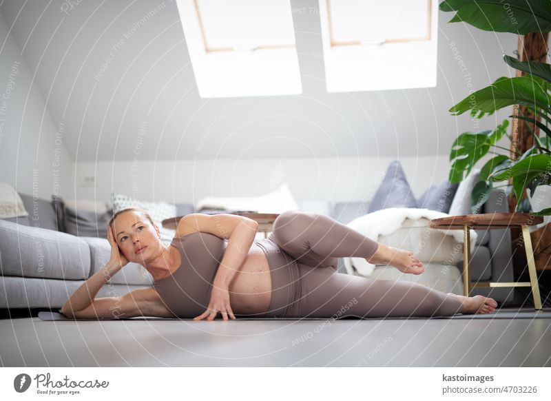 Young beautiful pregnant woman training pilates at home in her living room. Healthy lifestyle and active pregnancy and motherhood concept. yoga baby care