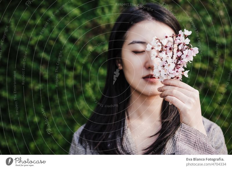 beautiful chinese asian woman holding almond tree flowers.Spring. selective focus on flowers portrait spring nature city oriental young green adult blossom day