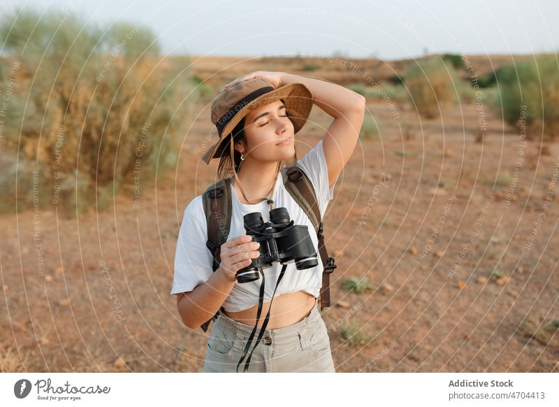 Woman with binoculars in desert field woman traveler trip adventure arid journey explore admire enjoy eyes closed content glad optimist pensive thoughtful