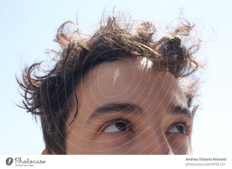 close up on a male teenager looking up face eyes closed eyes outdoor sunny hair curly horizontal color image boy relax dreaming portrait sky imaging caucasian