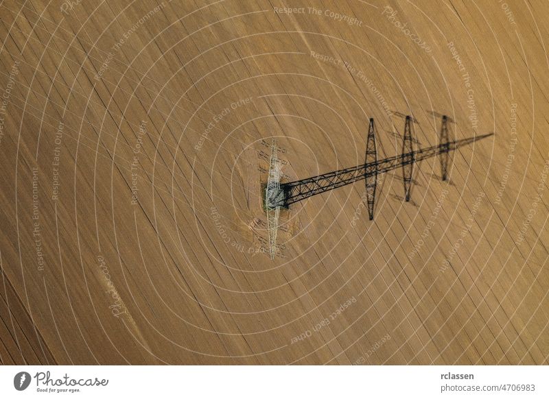 Aerial view of power line in a agricultural plowed field prepared for planting. shoot from drone directly above power pole aerial soil corn electricity dirt