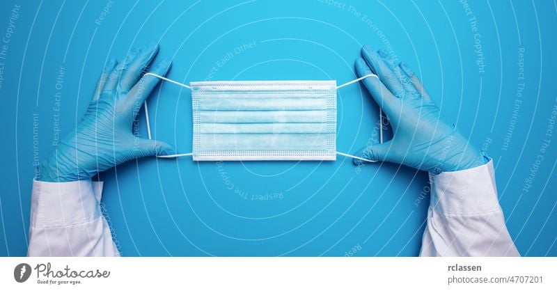 Doctor Hands in gloves showing medical face mask on blue background. Preventive measures to protect against Covid-19 Corona virus infection. 2019-ncov covid 19