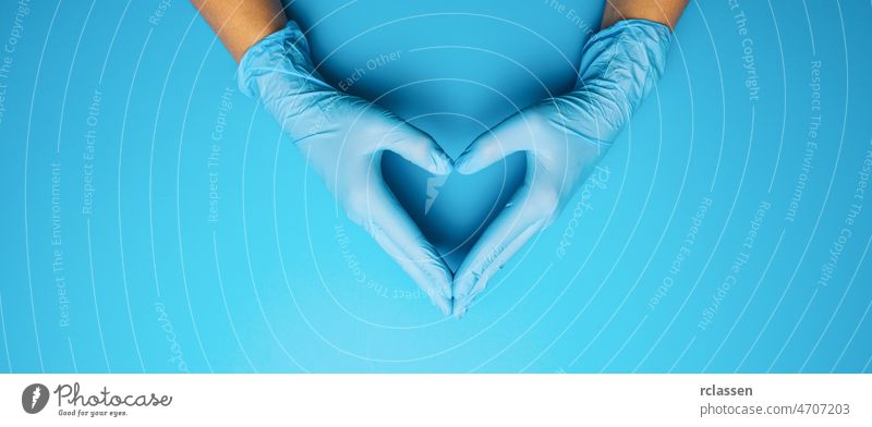 Doctor's hands in medical gloves in shape of heart on blue