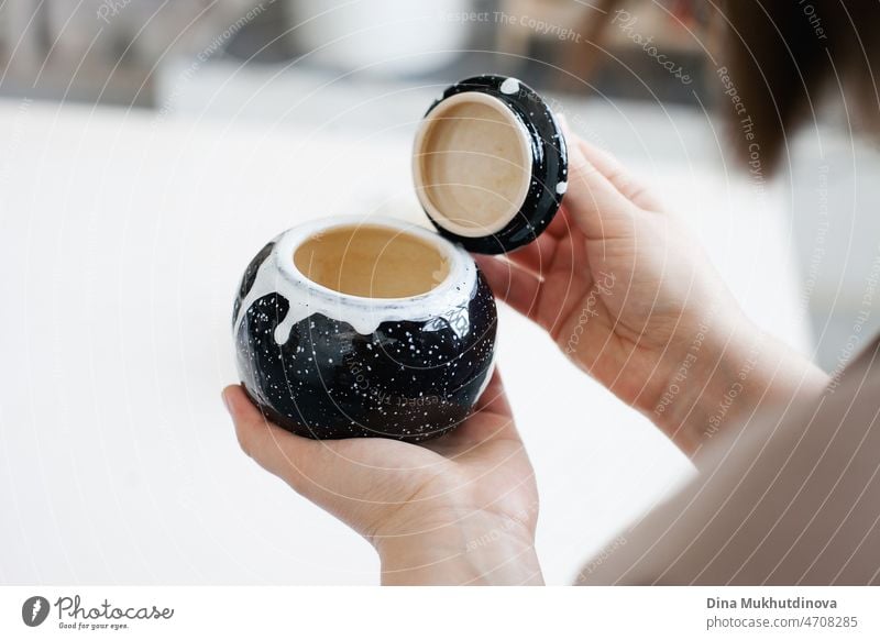 Woman holding artisanal black shining clay bowl in her hands, after creating it at pottery workshop. Art and craft, hobby and small female owned business.