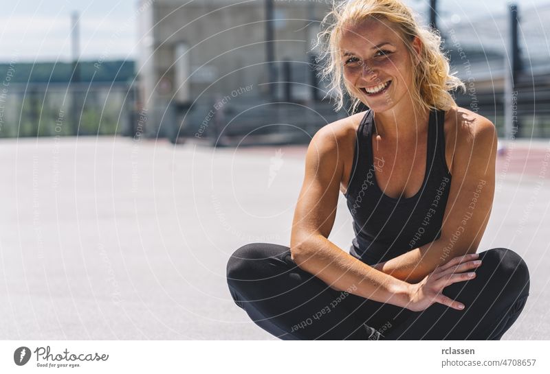 Outdoor shot of active brunette woman exercises with fitness ball poses at  green grass, dressed in active wear, enjoys sunny day and fresh air in  park, keeps fit, makes gymnastics exercises. 