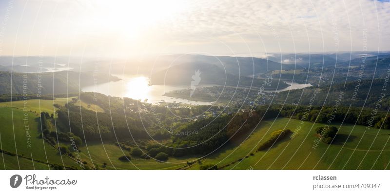 Lake Rursee at sunrise, Eifel Germany eifel rursee aerial blue drone green sunset national park nature outside panorama sun flare sunlight reservoir clouds sky