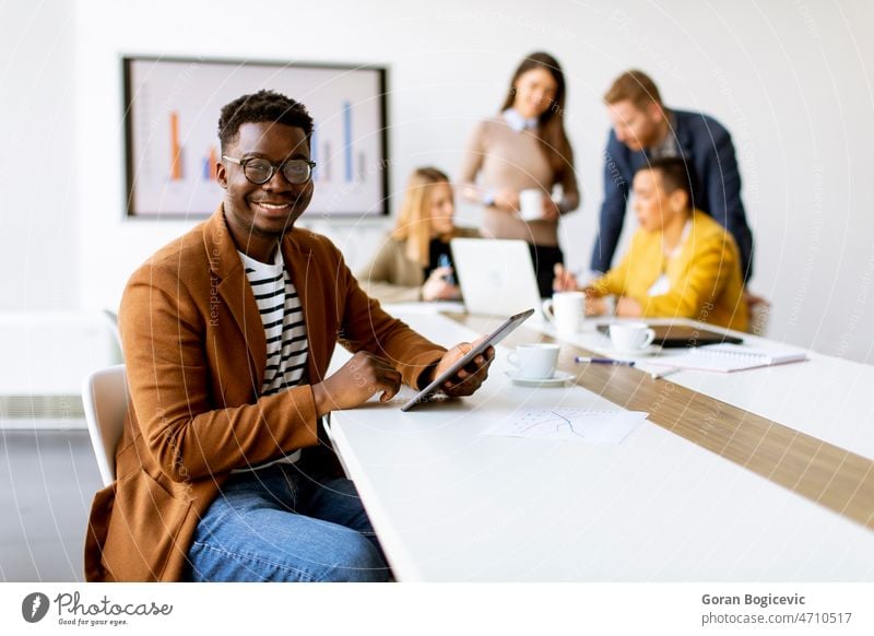 Young African American business man working with digital tablet in front of his coworkers at boardroom black brainstorming business meeting business team