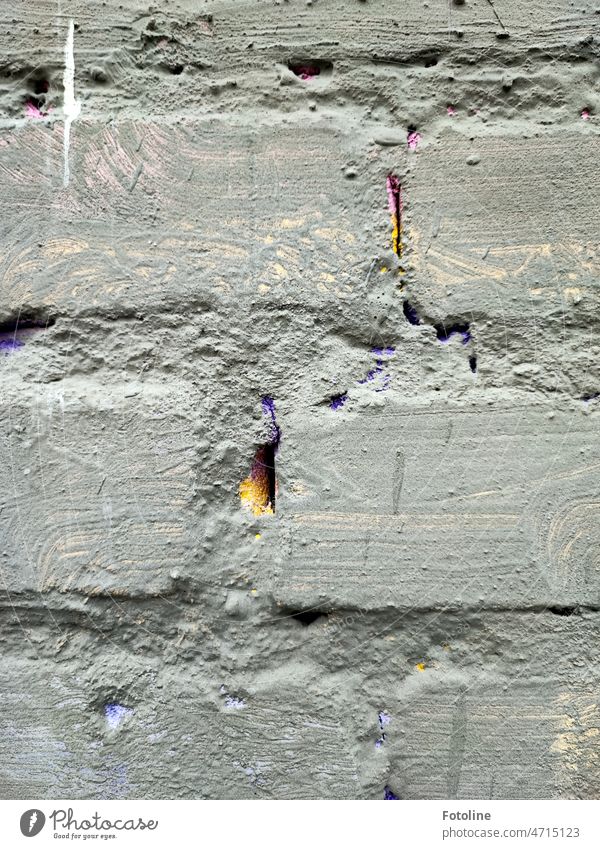 The gray painted wall was certainly once colorful. You can only see that in the joints. Yellow and purple shimmer through there. Wall (barrier) Brick