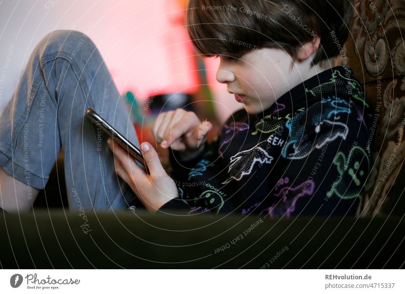 Child with smartphone Cellphone Boy (child) upbringing media pedagogy Digital Media usage Sit Sofa Interior shot Concentrate whatsapp 3 - 8 years Living room