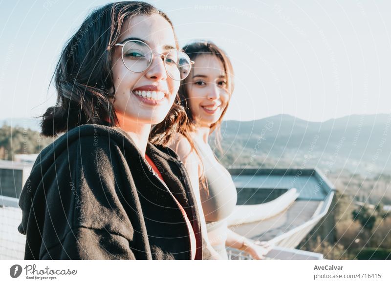 Portrait of two young woman looking from a lookout during a sunset after a workout exercise day. Training to relax after a working day with friends together. Young african woman