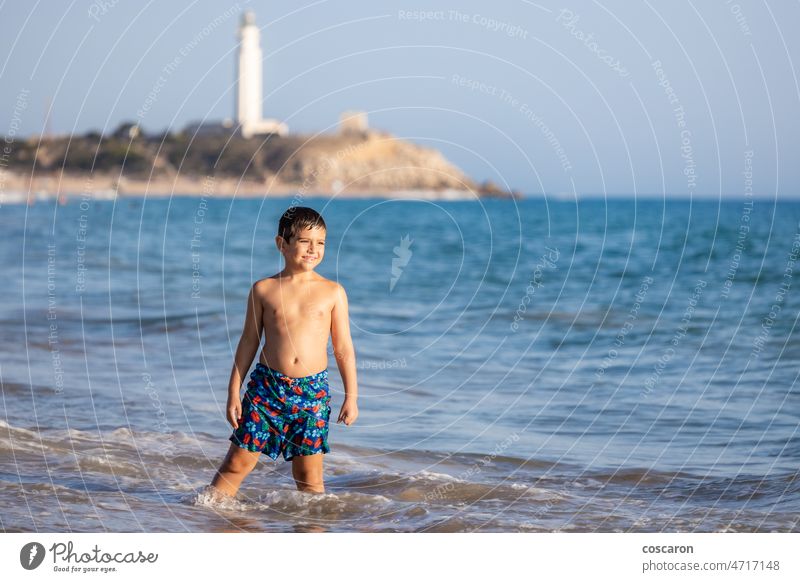 Funny kid enjoying the water of the ocean with a lighthouse background barbate beach boy cadiz child coast coastline el matador state beach evening fun golden