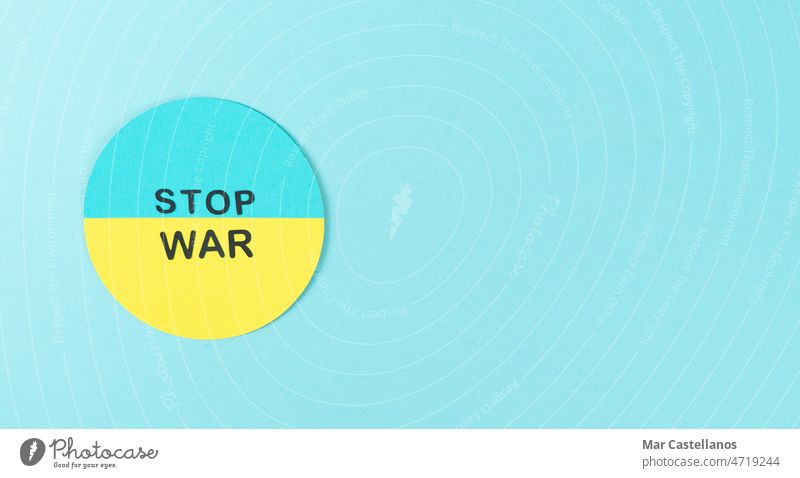 STOP WAR. Cardboard circle with Ukrainian flag and Stop war message. Copy space. Ukraine conflict invasion cardboard yellow blue copy space top view Russia