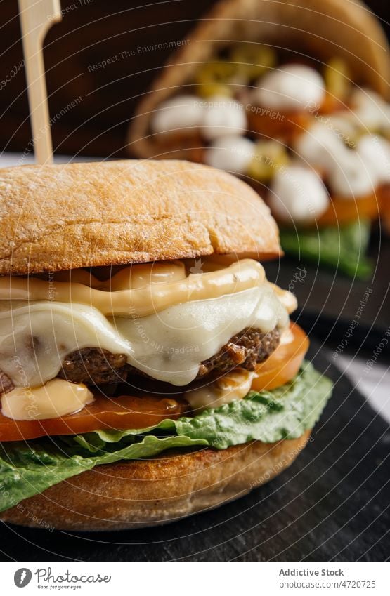 Delicious burger with melted cheese fast food cutlet tomato lettuce snack calorie gastronomy unhealthy delicious fried meal tasty appetizing kitchen skewer